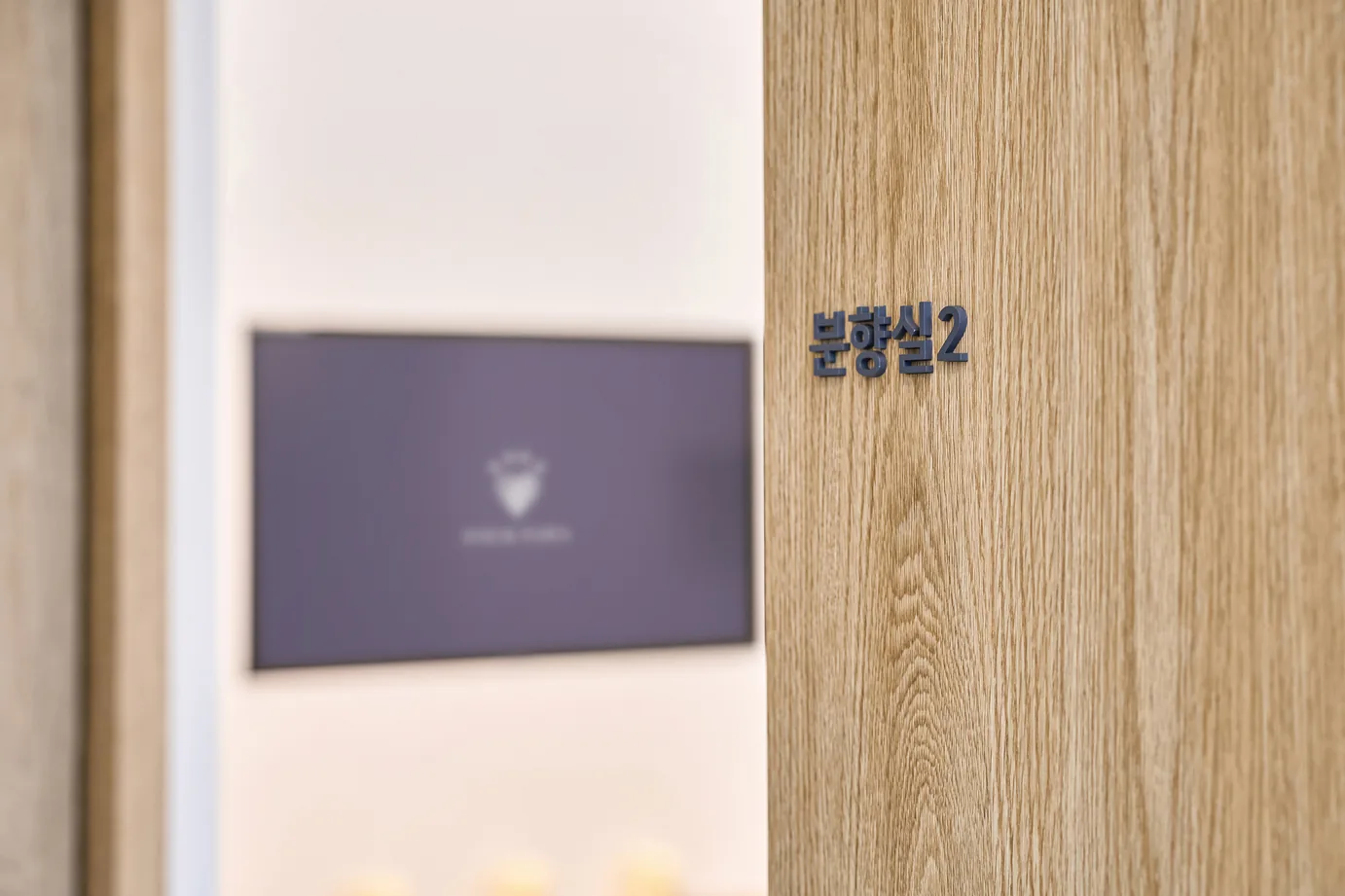 나무 결 문 옆 흰 벽에 분향실2 글자가 붙고 FOUR PAWS 로고가 뜬 작은 화면이 걸린 포포즈 세종점 분향실 입구